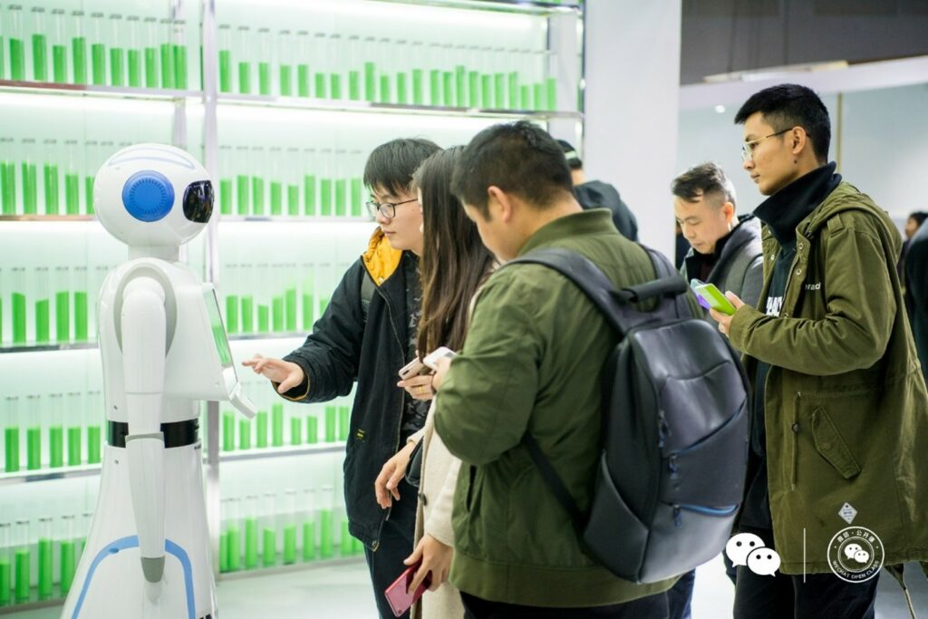 Junge Menschen schauen in der WeChat Zentrale Roboter an